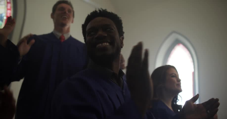 Choir members at a church sing and clap