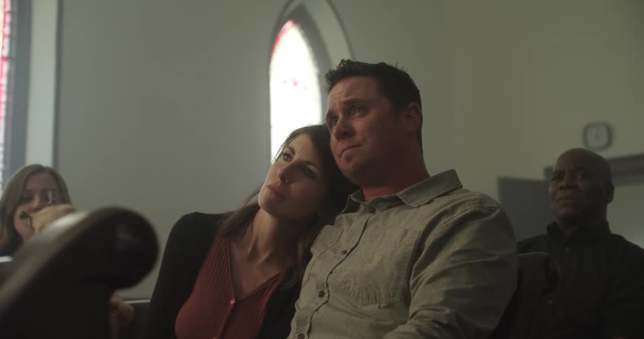 Man and woman sit close as they attend a church service