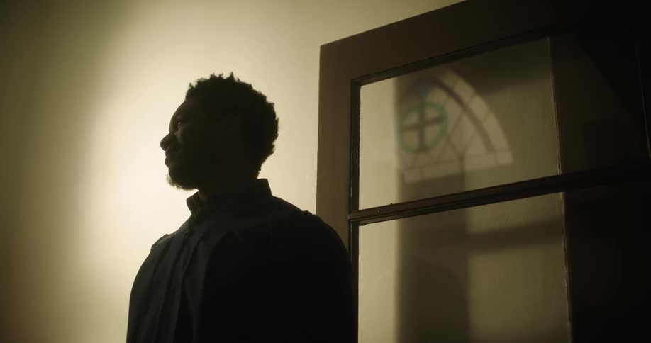 A man standing in a hallway gesturing while talking happily