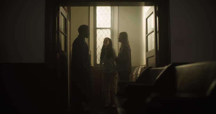A man talks to two women in a church all smiling and happy