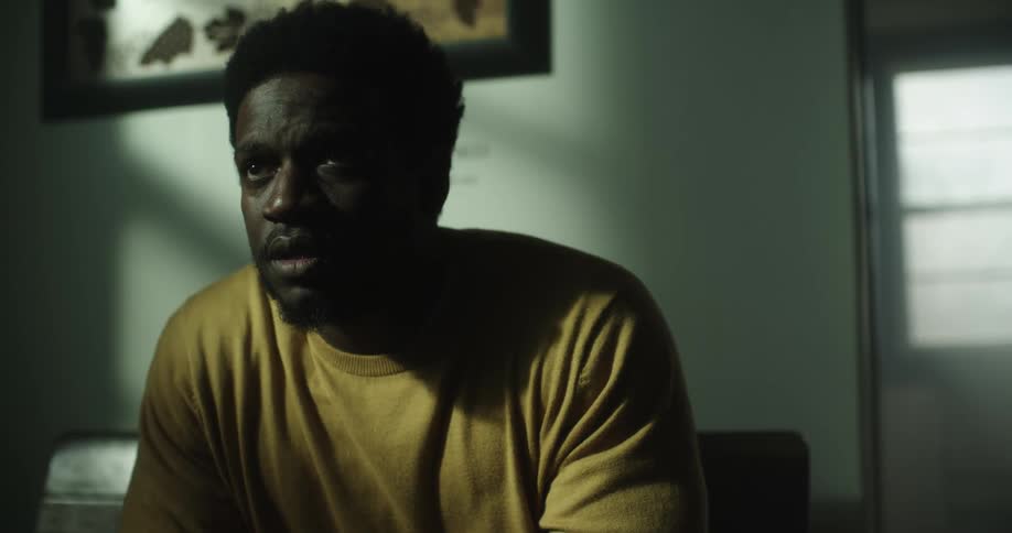 A man is sitting inside his house and looking sad