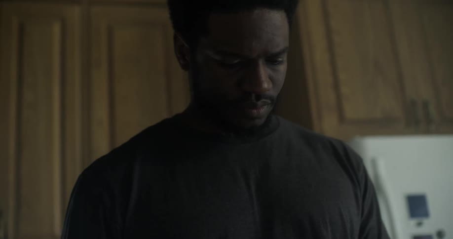 A black man stands in his kitchen