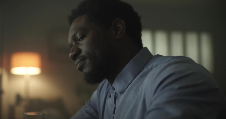 A black man sits in a room thinking