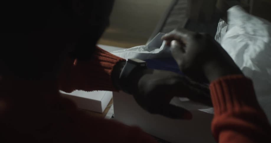 A black man opens a box containing a blue robe