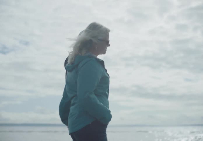A white couple walk on the beach while holding hands