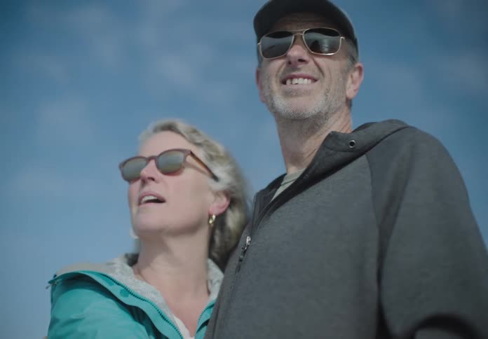 A couple stand outdoors laughing and hugging