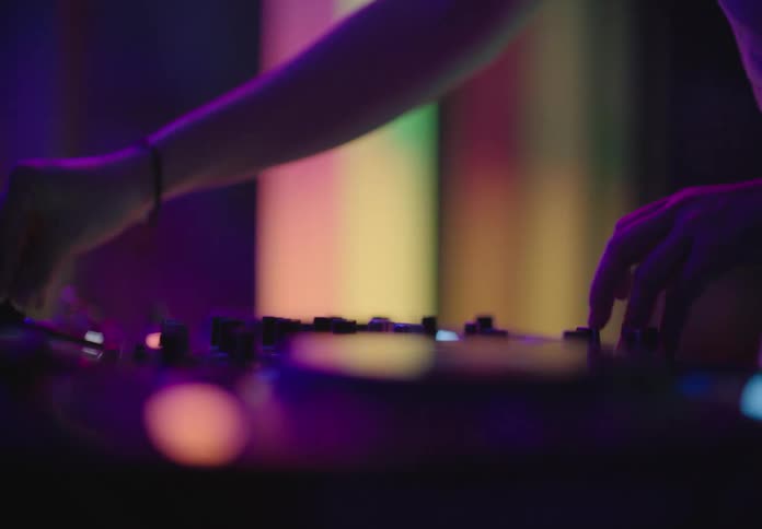 A musician spins dials on a soundboard to make music at a night club