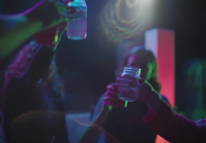 A group of friends sit in a club and drink alcohol
