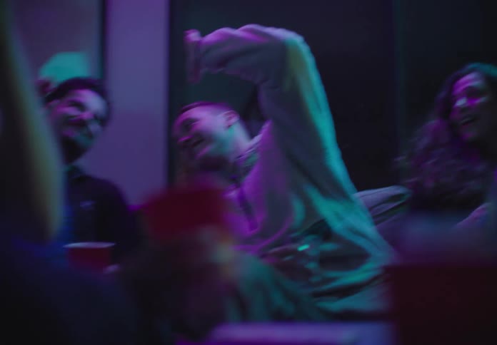 A group of friends sit around in a club drinking alcohol
