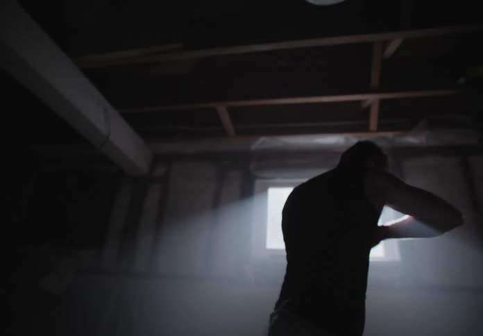 A man in a basement shadowboxing