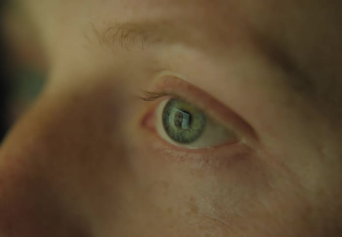 A persons eyes reflecting a smart phone video of another person
