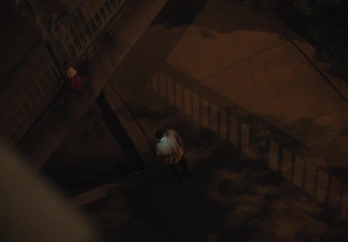A man walks outside and then stops to use his cell phone