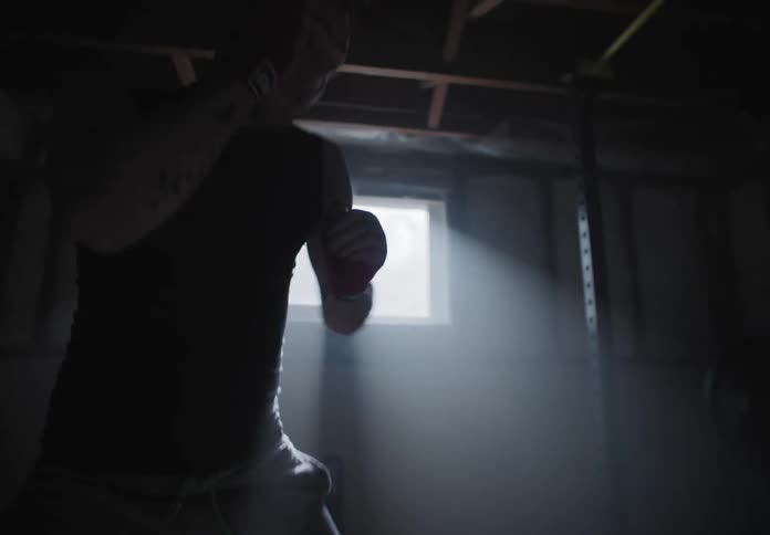 A man shadow boxes in his basement