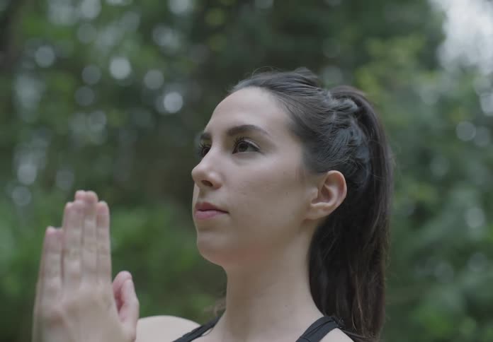 A young white woman performs yoga outdoors