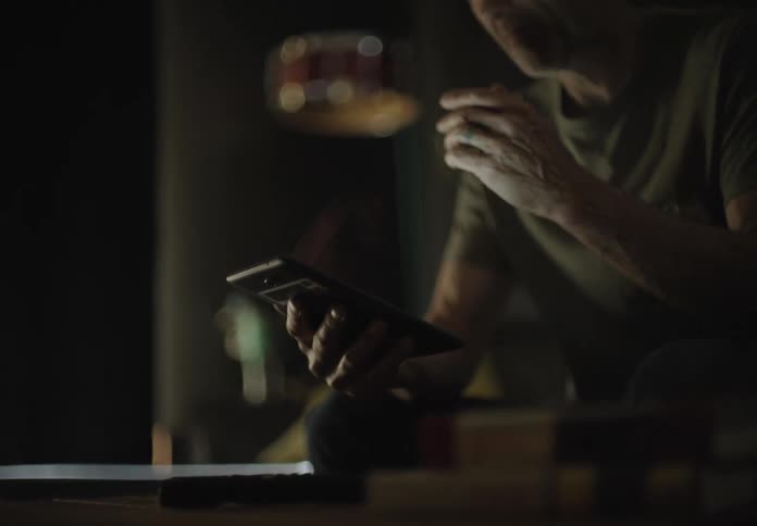 An older white man interacts with a smartphone