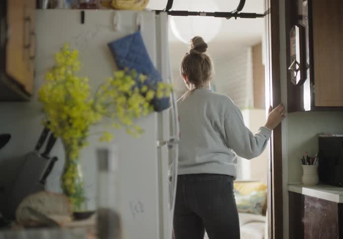 A woman in the kitchen adding salt to a fry egg
