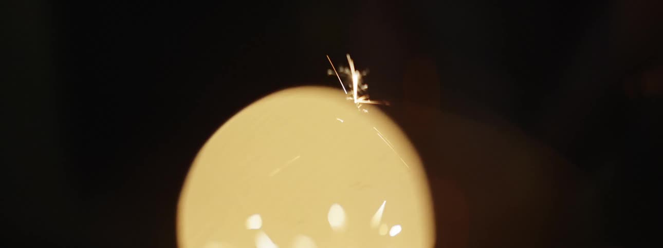 Sparks fly and glow at night from a sparkler