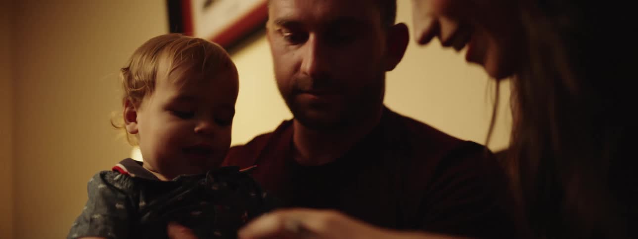 A mother takes a toy car away from her son as his father holds the infant and looks on