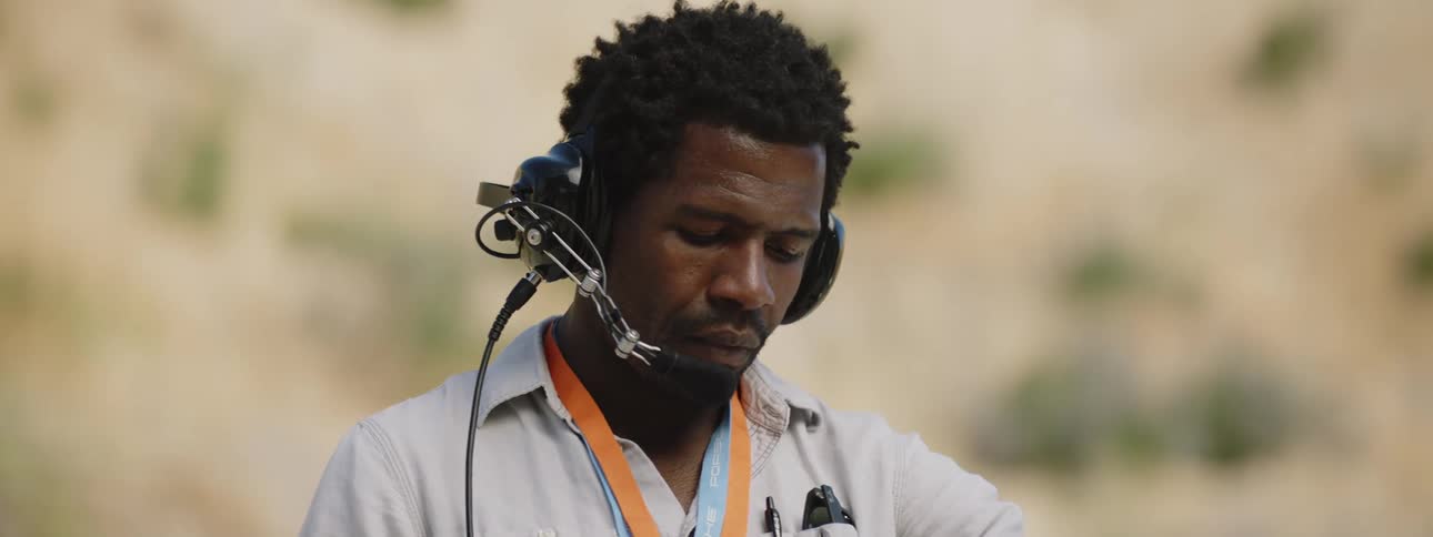 A man wearing a headset checks his watch