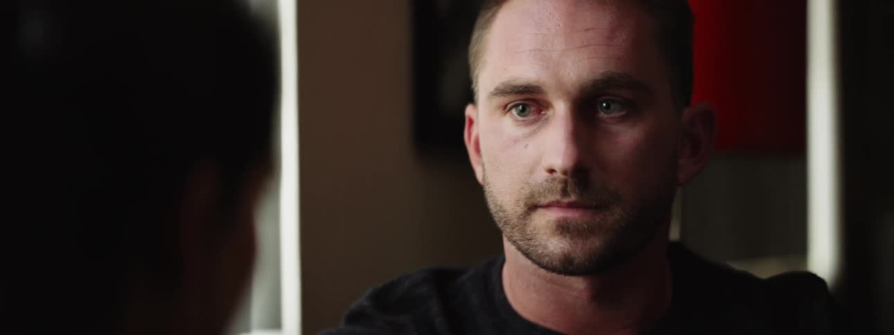 A white man looks downcast as he listens to someone else