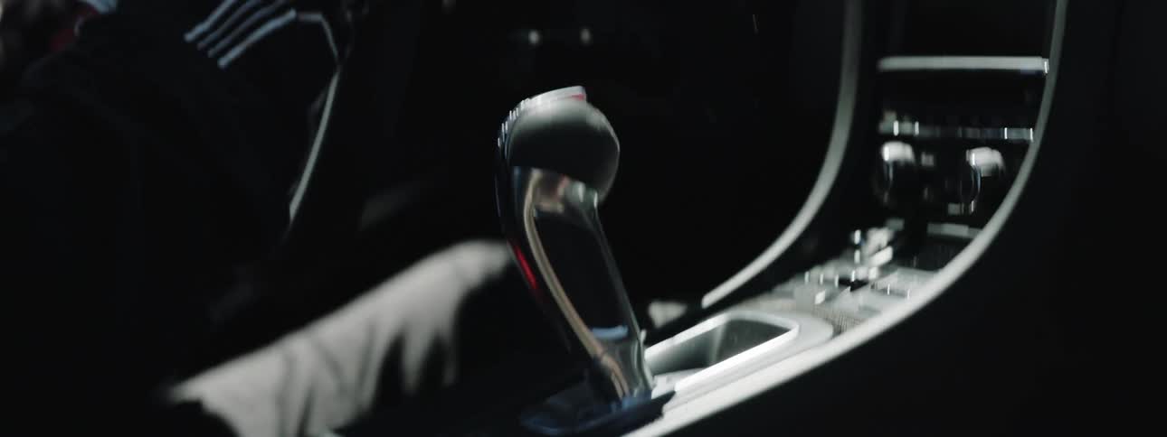A driver shifts the gear of a speeding sports car