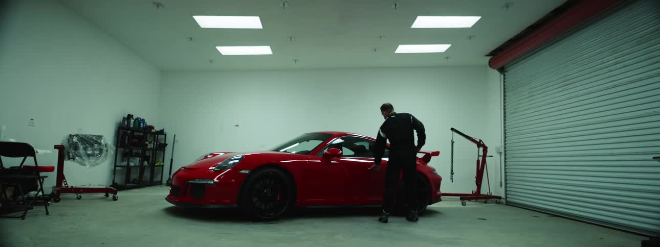 A man is in a garage and getting into a vehicle
