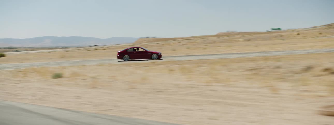 A red car races down a track out in a desert