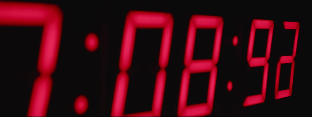 Digital clock shows advancing time in pink numbers on black background