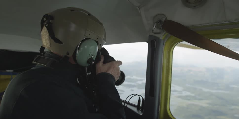 A man is taking photographs from inside a flying plane