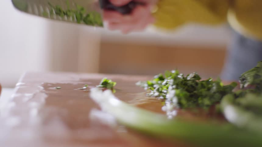 A white woman cuts up greens and an onion with a knife