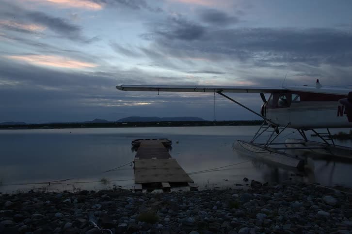 A time lapse of a plane docked in the water by rocks