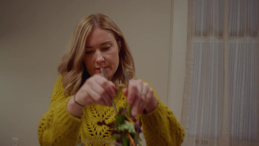 A white couple prepare to eat a meal at a dining room table