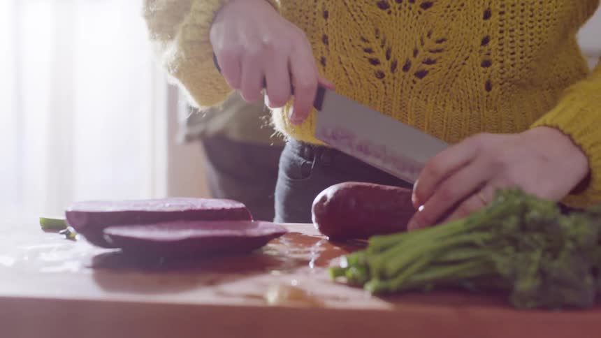 A woman cuts vegetables at home