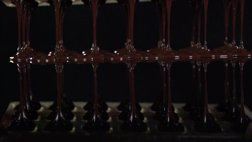 Liquid chocolate pouring from machine onto solid surface