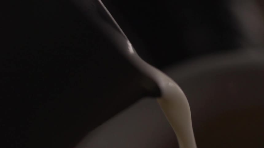 Thick cream is poured from a pitcher spout