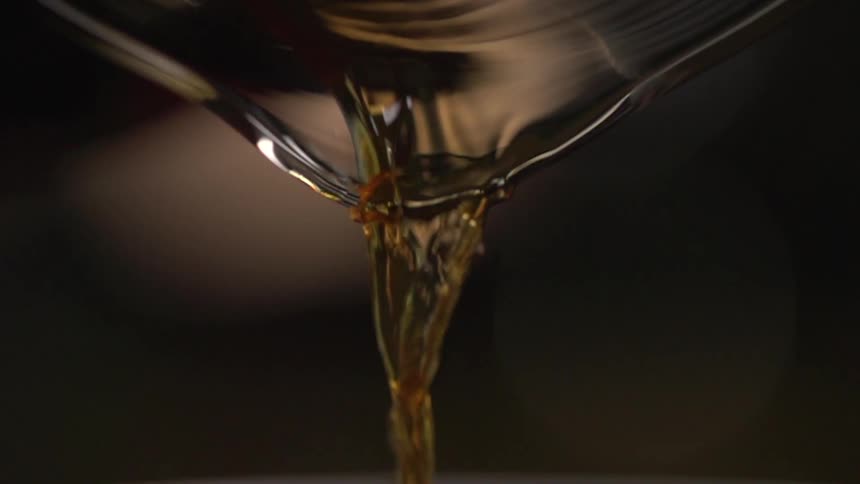 An amber liquid pours out of a glass pitcher