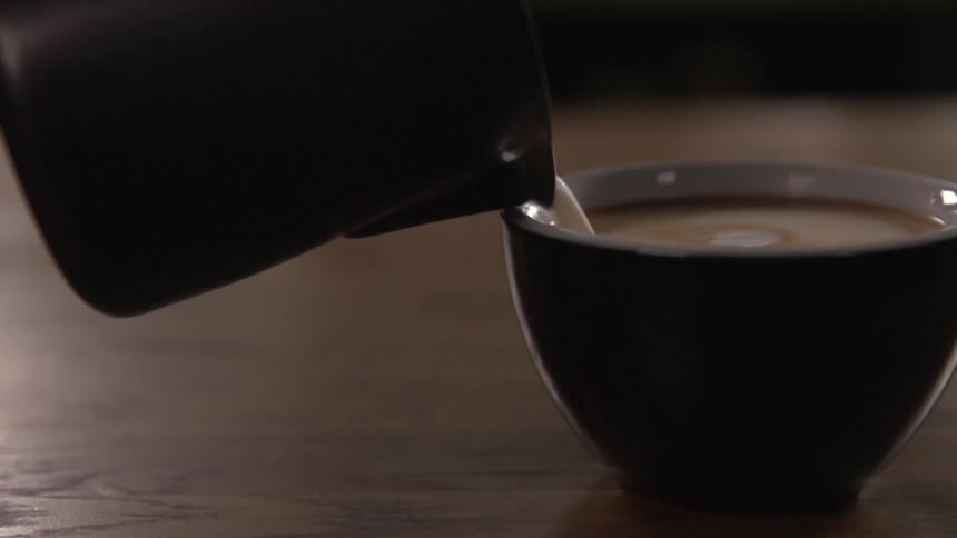 Cream being poured into a cup of coffee