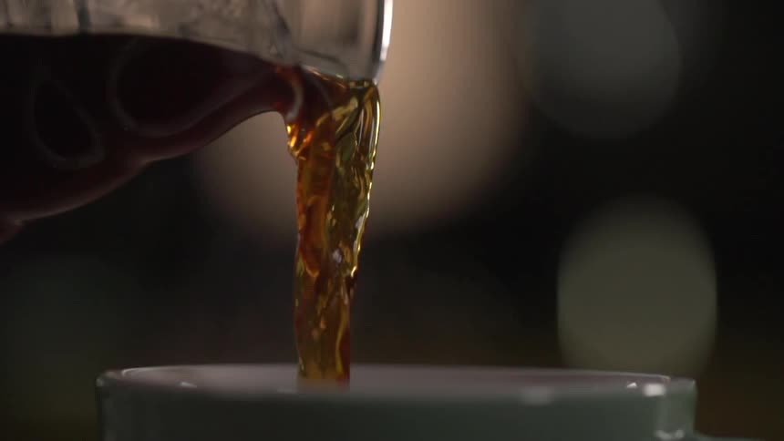 Coffee pours from a pitcher into a cup