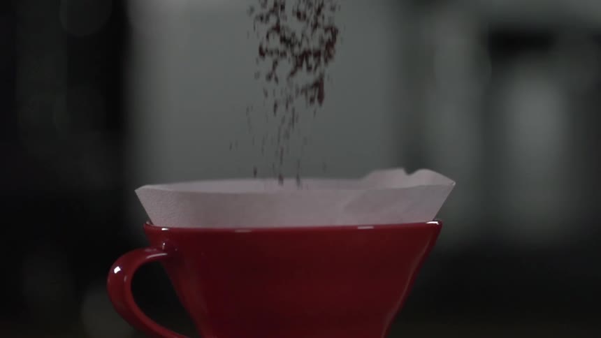 Coffee grinds dumped into a red cup with a filter in it
