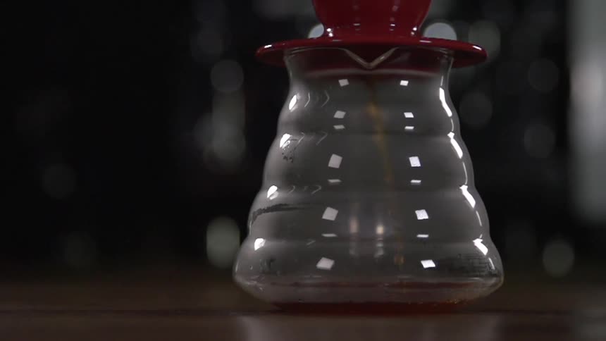 A brown liquid pours into a glass pitcher