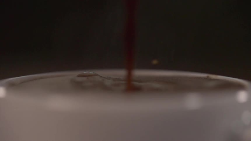 A thick liquid pouring into a white cup