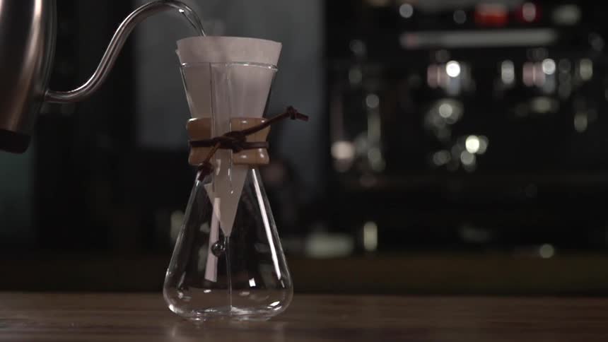 Water is poured from a teapot into a filter in a beaker