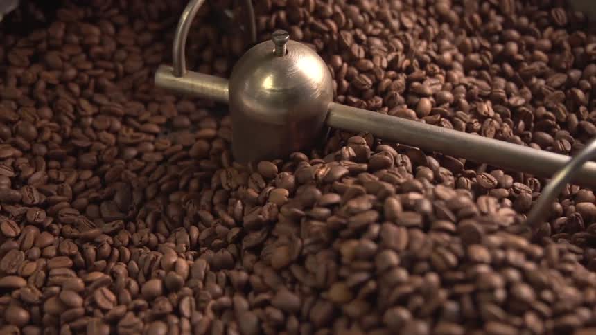 A machine spins coffee beans in a vat