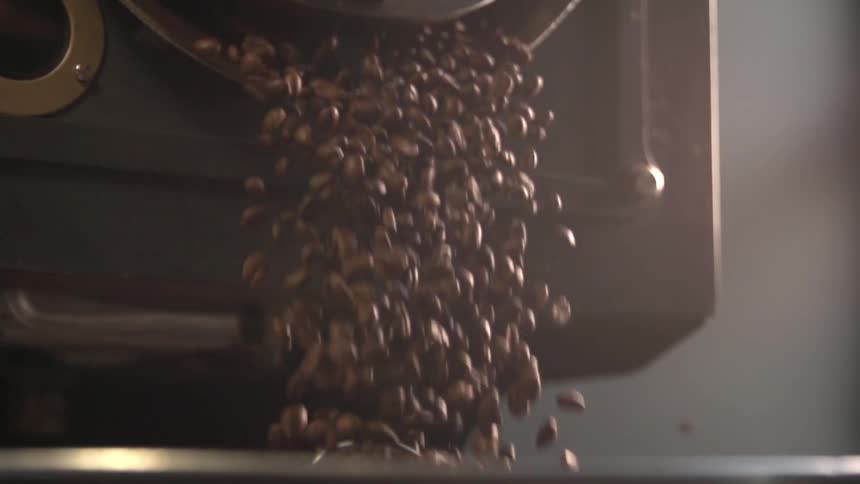 Coffee beans spill out of a roasting machine