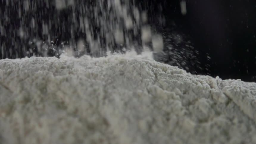 Flour falling into a mound against a black background