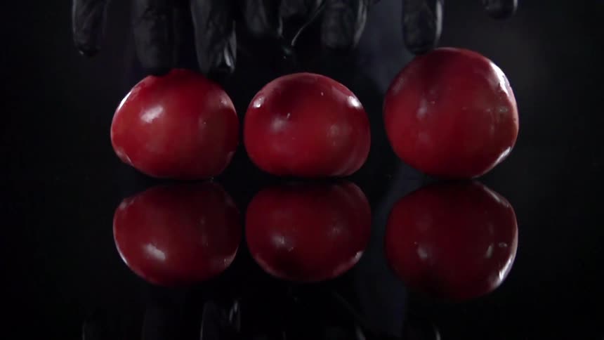 A person is setting three apples down on a table