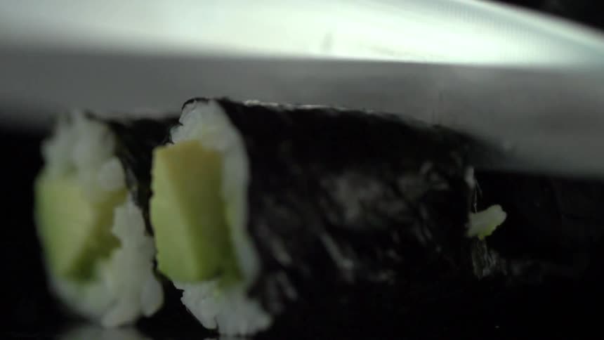 Chef knife slicing sushi rolls