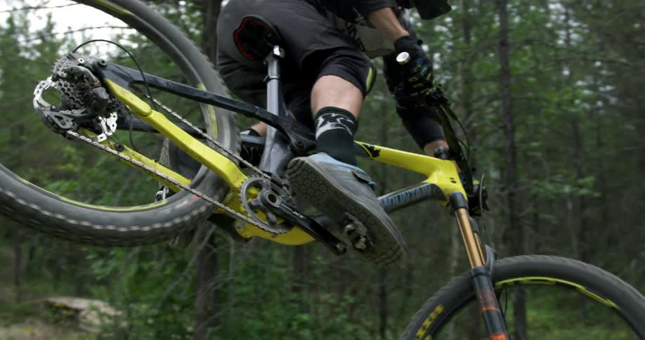 A man rides over a jump on a dirt path