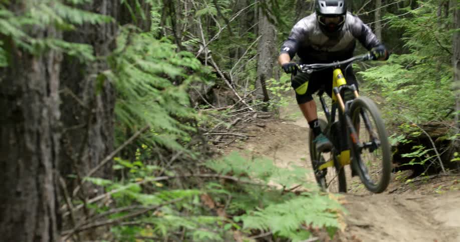 A mountain biker quickly rides high speed corners down trail
