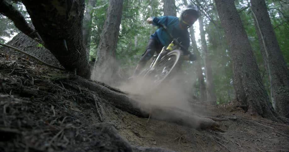 Two mountain bikers riding down a dusty trail in a forest